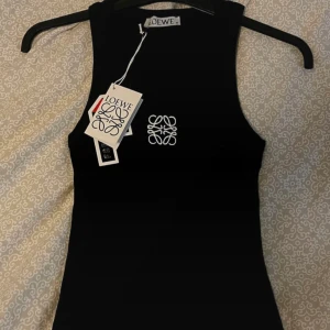 Svart linnetopp från Loewe - Supersnygg svart linnetopp från Loewe med broderad vit logga på bröstet. I nyskick, storlek M. Köpt på Farfetch.