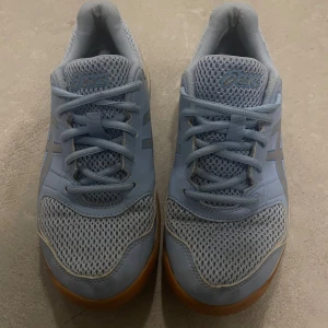 Ljusblå Asics sneakers  - Snygga ljusblå Asics sneakers med meshpaneler för extra andningsförmåga och klassisk logga på sidan. Skorna har snörning och en gummisula i kontrasterande färg. Perfekta för dig som gillar sportig stil och vill ha bekväma skor till träning eller vardag.