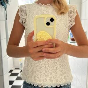 Vit spetsblus från Lindex - Superfin vit blus från Lindex i spets med blommigt mönster och scallop-detaljer vid ärmslut och nederkant. Ärmlös modell med snygga spetskanter på axlarna. Perfekt till jeans eller kjol för en söt och fräsch look.