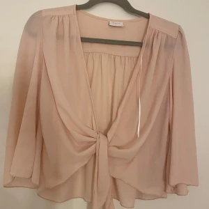 Ljusrosa blus med knyt från Vila - Superfin ljusrosa blus från Vila i tunn polyester. Blusen har v-ringning och snygg knytning framtill. Passar till både jeans och kjol!