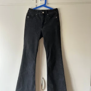 Svarta bootcut jeans från H&M Divided - Snygga svarta bootcut jeans från H&M Divided i storlek 34. Jeansen har klassisk femficksdesign, hög midja och utsvängda ben. Tillverkade i mjukt bomullsmaterial med lite stretch för extra komfort. Perfekta för dig som gillar en retroinspirerad look.