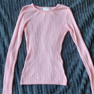 Rosa ribbad långärmad tröja H&M XS - Supersöt ljusrosa lite genomskinlig ribbad tröja från H&M i storlek XS. Tröjan har lång ärm, rund halsringning och är figurnära i modellen. Perfekt att styla med jeans eller kjol för en fräsch look.