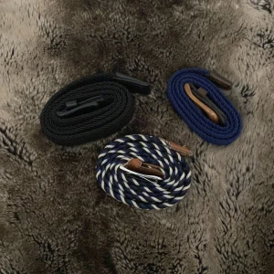 3 flätade bälten i olika färger - Säljer tre snygga flätade bälten: ett helsvart, ett marinblått och ett randigt i blått, svart och vitt. Alla har detaljer i brunt läder och metallspänne. Perfekt accessoar för att lyfta din outfit med en sportig och stilren touch. De svart, blå och vit randiga bältet är i sämre skick men dom andra två är i bra skick! Säljer alla tre för 100 men 35kr styck. Kom med bud och frågor!