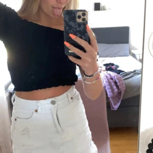Svart offshoulder croppad topp - Säljer en svart offshoulder topp med puffiga korta ärmar och resår vid axlar och midja. Toppen är croppad och har en luftig, lite lös passform. Perfekt för dig som gillar en trendig och avslappnad stil.