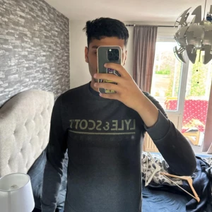 Mörkgrå sweatshirt från Lyle & Scott - Säljer en stilren mörkgrå sweatshirt från Lyle & Scott med logga tryckt framtill. Tröjan har rund hals, långa ärmar och ribbade muddar vid ärmslut och nederkant. Perfekt för en avslappnad och snygg look.