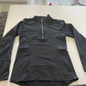 Svart träningströja OTP Extreme XS - Sportig svart långärmad träningströja från OTP Extreme i storlek XS. Tröjan har en smickrande passform, half zip-dragkedja framtill och är tillverkad i ett mjukt syntetmaterial som andas. Perfekt för löpning eller gymmet.