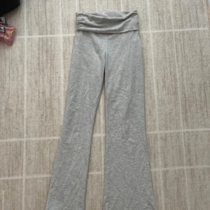 Grå bootcut yogapants - Snygga grå yogapants med bootcut-ben och bred, vikbar midja. Byxorna är i mjukt bomullsmaterial och har en avslappnad passform som är perfekt för chill dagar eller träning. Enkla att matcha med en hoodie eller crop top.