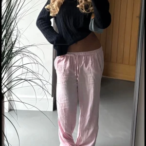 Rosa randiga linnebyxor med snörning - Luftiga och sköna linnebyxor i ljusrosa med vita ränder. Byxorna har elastisk midja med snörning och raka ben. Perfekta för chill dagar eller när du vill ha en avslappnad vibe. Materialet är linneblandning som känns svalt och mjukt mot huden.