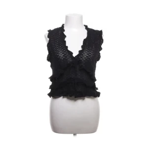 Svart spetsigt ärmlös topp från MNG - Supersnygg svart ärmlös topp från MNG med spetsdetaljer och volanger. Djup v-ringning och figurnära passform, perfekt för att lyfta vilken outfit som helst.