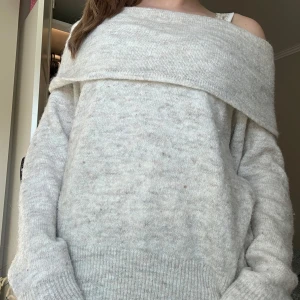 Offshoulder stickad tröja i ljusbeige - Mysig offshoulder stickad tröja i ljusbeige med bred krage som vilar över axlarna. Tröjan har lång ärm och en avslappnad passform, perfekt för lager-på-lager under kyliga dagar. Använd fåtal gånger 💕