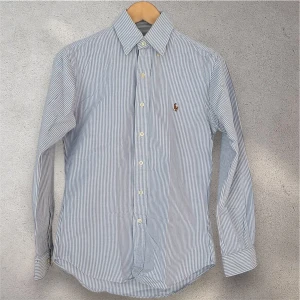 Ralph Lauren Skjorta - Ralph Lauren skjorta i utmärkt skick! Den är i storlek XS och har en riktigt fin färgkombination med blåvita linjer! Ordinarie pris: 1 585 kr! Vid eventuella frågor eller funderingar är det bara att hojta till! 