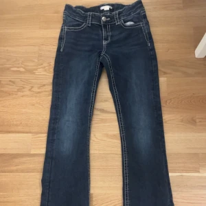 Mörkblå jeansbyxor med broderade bakfickor från Gina Tricot - Snygga mörkblå botcut jeans från Gina Tricot med kontrastsömmar och unika broderade detaljer med paljetter på bakfickorna. Storlek 158. 150kr