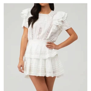 Vit spetsklänning med volang - Superfin vit kortklänning med spetsdetaljer och volanger på axlarna. Klänningen har rund halsringning, korta ärmar och en luftig kjol med lager. Storlek S men skulle säga att den är lite stor i storleken, skulle nog passa mer i M