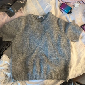 Grå stickad kortärmad tröja från Zara - Mysig grå stickad tröja från Zara med korta ärmar och rund halsringning. Perfekt för lager-på-lager och passar till både jeans och kjol. Mjuk och skön känsla i materialet. nästan aldrig använd därför jag säljer denna tröjan för att någon annan får mer användning av den än mig❤️