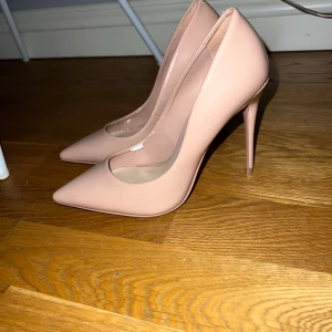 Nude pumps med spetsig tå och hög klack - Säljer ett par stilrena nude pumps från Aldo med spetsig tå och hög smal klack. Skorna har en elegant och minimalistisk design i syntetmaterial och passar perfekt till dig som vill ha en klassisk look.