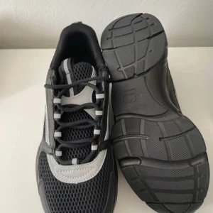 Svarta Dior B22 - Säljer ett par svarta Dior sneakers med grå och vita detaljer. Skorna har meshpaneler för extra andningsförmåga, rund tå och platt sula. Snygg och sportig design med tydlig Dior-logga på sidan. Perfekta för dig som gillar exklusiva och trendiga sneakers. Pris kan sänkas vid snabb och smidig affär!!