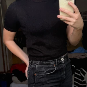 Svart stickad t-shirt från ONLY med glitter - Säljer en svart stickad t-shirt från ONLY. T-shirten har rund halsringning och korta ärmar. Materialet är tunt och lätt genomskinligt vilket ger en snygg look. Perfekt att styla med jeans eller kjol. Använt en gång och är gjort av ett glittrigt material. 