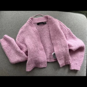 Ljusrosa stickad kofta från Gina Tricot - Superfin ljusrosa stickad kofta från vero moda. Modellen är croppad med lång ärm och bred ribbad kant vid ärmslut och öppning. Perfekt att slänga över en topp för en mysig look.