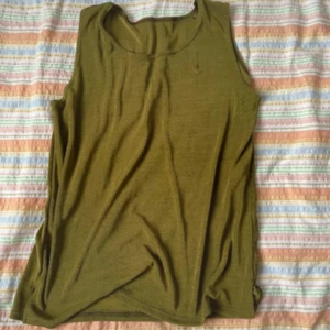 Olivgrön linnetopp - Säljer en enkel olivgrön linnetopp med rund halsringning. Toppen är ärmlös och har en rak passform, perfekt för varma dagar eller som lager under andra plagg.