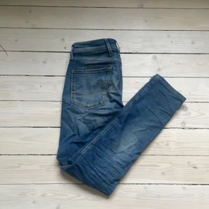 Blå slim fit jeans från Replay Anbass - Säljer ett par blå Replay Anbass jeans i slim fit-modellen. Jeans med snygga slitningar och normal midja. Perfekta för dig som gillar en smalare passform och stilren look. Byxorna är 28W 34L men har blivit nersydda till 28W 30L.