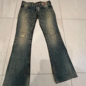 Lågmidjade vintage jeans  - Vintage Low Waist Bootcut jeans från Vicious med broderade detaljer i rött och vitt, super coola men alldeles för små för mig tyvärr:(.            Mått:  Midja 38 cm Grenlängd 20 cm Innerbenslängd 74 cm Fotöppning 22 cm