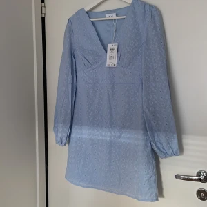 Ljusblå Vila malina klänning  - Säljer en helt ny Vila malina klänning i ljusblått. Långärmad klänning i 100% bomull. Skönt material och bra passform. Ordinarie pris 799