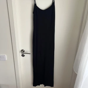 Svart långklänning  - En stilren svart långklänning från Gina Tricot, med smala axelband och figurnära passform. 