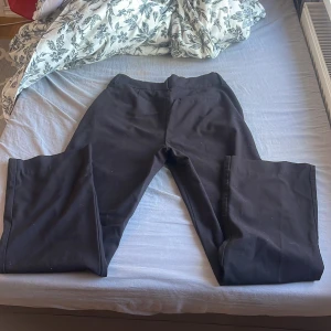 Svarta kostymbyxor från First Class Collection - Säljer ett par svarta kostymbyxor från First Class Collection i klassisk rak modell. Byxorna har normal passform, bälteshällor och stängs med dragkedja och hake. Perfekta till en stilren look.