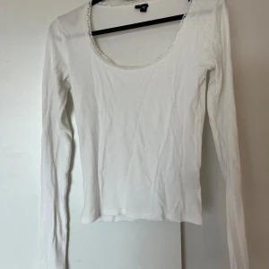 Vit långärmad topp med spetskant från H&M - Säljer en enkel och stilren vit långärmad topp från Lager157. Toppen har en rundad urringning med fin spetskant och är tillverkad i mjukt bomullsmaterial. Perfekt att matcha med jeans eller kjol.