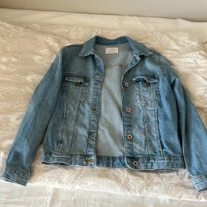 Ljusblå jeansjacka från Zara - Säljer en klassisk ljusblå jeansjacka/ denimjacket  från Zara med bröstfickor och knappar framtill. Jackan har krage och långa ärmar, perfekt för lager-på-lager-stil. Enkel och tidlös design som passar till mycket! Perfekt till sommaren / våren, Endast använd 1 gång annars orörd, Storlek 152//XS💕💕Pris kan diskuteras privat🙏