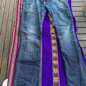 Blå jeans från Nudie Jeans Co - Säljer ett par klassiska blå jeans från Nudie Jeans Co med orange sömmar och läderpatch bak. Jeansen har normal passform och raka ben, perfekt för dig som gillar en tidlös stil. Storlek w36 l34. Inga skador eller så! Säljes från garderoben för dom inte kom till användning