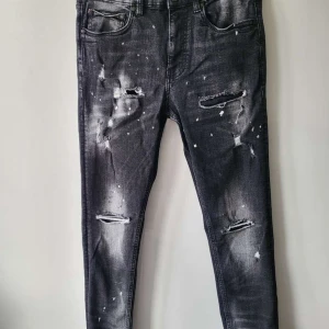 Svarta jeans  - Snygga svarta jeans från Supply & Demand med slitna detaljer och en cool tvättad look. De har en tight passform och är perfekta för en trendig stil. Midjan är midwaist och byxorna har klassiska fem fickor.