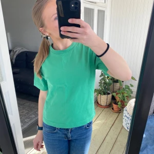 Grön t-shirt från Gina Tricot - Säljer en fräsch grön t-shirt från Gina Tricot. Den är kortärmad och har en enkel, stilren design. Perfekt för en avslappnad look. Passar bra till jeans eller shorts.
