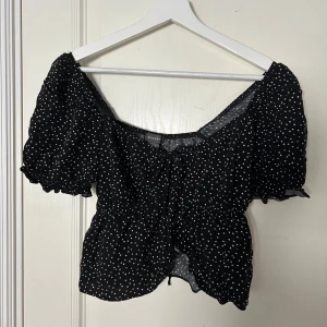 Svart prickig blus  - Säljer en söt svart blus med vita prickar. Blusen har korta puffärma. Fint skick!
