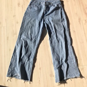 Blå jeansbyxor - Snygga blå jeansbyxor med en loose passform och fransiga kanter. Perfekta för en avslappnad stil. De har en klassisk femficksdesign och är tillverkade i ett slitstarkt denimtyg.