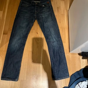 Mörkblå jeans från Replay - Snygga mörkblå jeans från Replay med klassisk femficksdesign och knappgylf. Perfekta för en avslappnad stil. Märkeslappen på baksidan ger en extra touch av stil.
