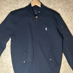 Mörkblå bomberjacka från Ralph Lauren - Säljer denna polo Ralph lauren bomberjackan köpt på macy’s i New York för ca 220 dollar. Storleks XS men passar S mitt pris är 800 kan kanske gå ner lite i pris beroende på affär. Endast prlvtestad 2-3 gånger så i nyskick!