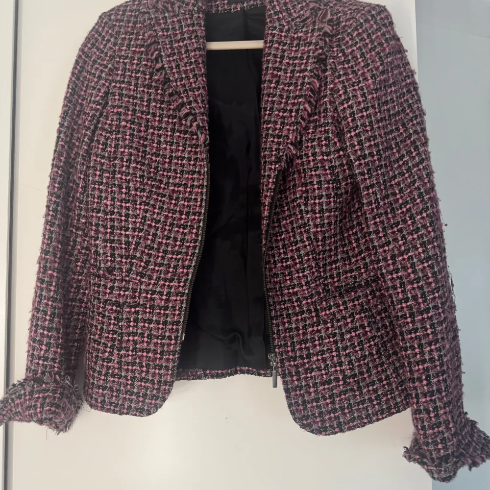 Snygg rutig kavaj i rosa och svart från Kello. Kavajen har en klassisk passform med fransiga detaljer vid ärmslut och krage. Perfekt för att ge din outfit en chic touch.. Takit.