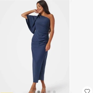 Marinblå oneshoulderklänning - Elegant marinblå klänning med oneshoulder-design och asymmetrisk ärm. Klänningen är ALDRIG använd, etiketten sitter kvar.