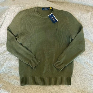 Olivgrön stickad tröja från Polo Ralph Lauren - Säljer en helt ny stickad tröja från Ralph Lauren, fortfarande med lappen kvar. Klassisk och stilren design i en snygg militärgrön färg, perfekt för både vardag och mer uppklädda tillfällen.  Märke: Polo Ralph Lauren Storlek: S Skick: Helt ny, oanvänd med tag kvar. Pris kan diskuteras  Tröjan är av hög kvalitet, bekväm och har den ikoniska broderade Polo Ralph Lauren-logotypen på bröstet. Ett perfekt tillskott till garderoben för en tidlös och stilren look.  📩 Hör av dig om du vill ha fler bilde