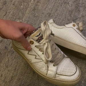 Vita läder sneakers från Zadig & Voltaire - Snygga vita sneakers från Zadig & Voltaire med perforerat mönster och blixtdetalj på sidan. Skorna har snörning och en rund tå. Skorna har lite användnings skador annars i jättefint skick🫶🏼kommer med tillhörande låda och dustbag. Pris går att diskutera!! 