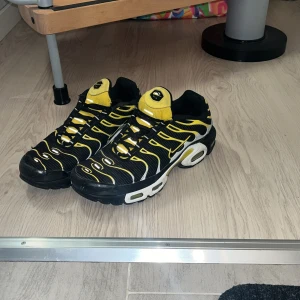 Nike tn  - Säljer ett par Nike tns i svart och gul. Skorna har en iögonfallande design med vågformade detaljer och en bekväm sula. Perfekta för dig som vill ha en unik stil.
