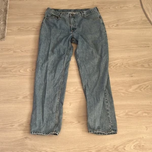 Blå jeans från Lee - Säljer ett par klassiska blå jeans från Lee. De har en rak passform och är tillverkade i denim med en traditionell femficksdesign. Perfekta för en avslappnad stil. Dem är stora vid midjan och minskas lite ner mot benen.