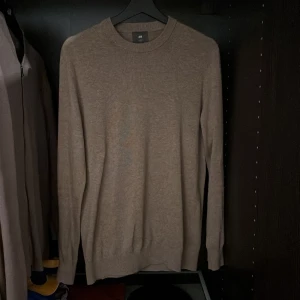 Beige tröja från H&M - Säljer en stilren beige/brun tröja från H&M i slim fit. Tröjan är långärmad och tillverkad i bomull, vilket gör den bekväm och perfekt för både vardag och lite finare tillfällen. Inga defekter eller liknande. Skriv vid eventuella funderingar. 