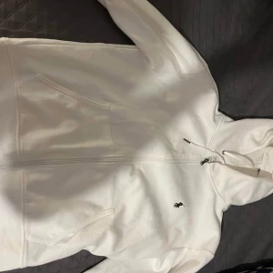  Polo Ralph Lauren - Säljer en stilren vit hoodie från Polo Ralph Lauren med dragkedja och det klassiska logotypbroderiet på bröstet. Tröjan har långa ärmar och en justerbar huva med snören. Perfekt för en avslappnad look. Pris kan diskuteras 