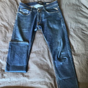 Blå jeans från Replay - Snygga blå jeans från Replay med klassisk femficksdesign och kontrastsömmar. De har en normal passform och är perfekta för en avslappnad stil. Märkeslappen på baksidan ger en extra touch av stil.