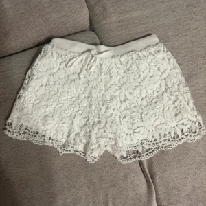 Vita spets shorts - Buda gärna💕 Säljer ett par vita virkade shorts med vacker spetsdesign och elastisk midja. Perfekta för en somrig look med en touch av elegans. De har en bekväm passform och är lätta att matcha med olika toppar🤍