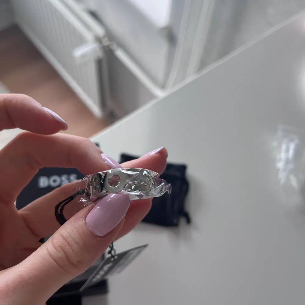 Stilren stålring från Hugo Boss med utskuren textdesign. Perfekt för att ge en elegant touch till din stil. Kommer i en snygg förpackning med en praktisk förvaringspåse. Köpte till min kille men den var för stor. Skickas i samma katrong den kom i från Zalando. Nypris 1035kr, pris kan diskuteras!. Asusteet.