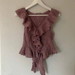 Lila volangblus från Zara - Säljer en lila blus från Zara med volangdetaljer och v-ringning. Aldrig använd. Storlek S. 