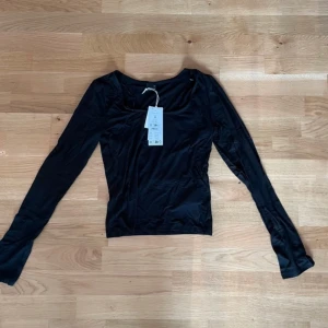 Svart långärmad topp från Gina Tricot - Säljer en svart långärmad topp från Gina Tricot i mjukt jerseytyg. Perfekt för en stilren look. Toppen har en enkel design som gör den lätt att matcha med olika outfits.